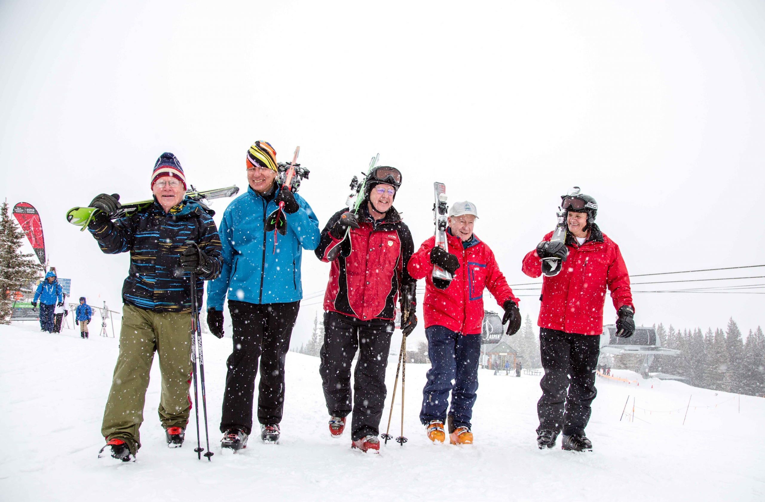 Five senior PSIA members walk from the gondola at Aspen Mountain carrying their skis over their shoulders
