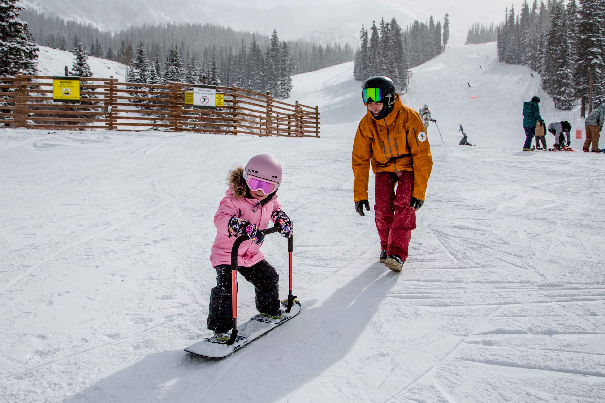 AASI Team member Tony Macri teaches a three-year-old to snowboard.