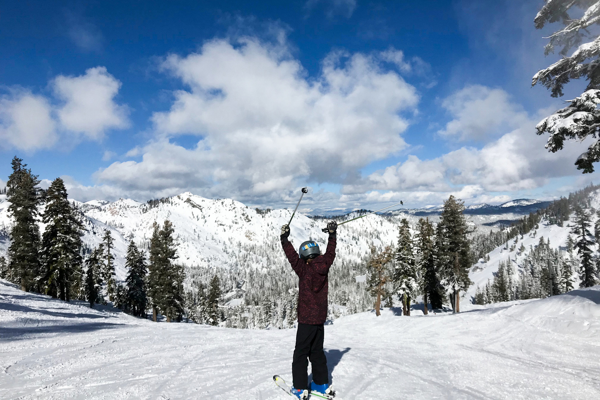 A person skis with their poles above their head in celebration.