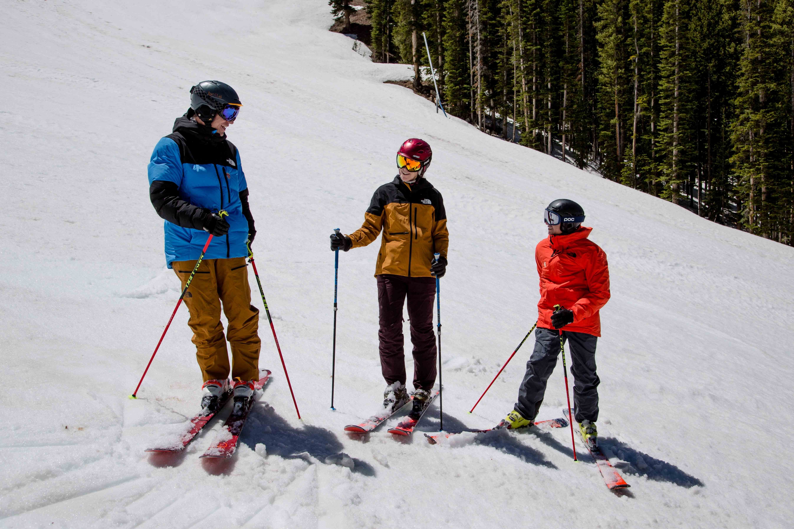 Three ski instructors talk on the hill.