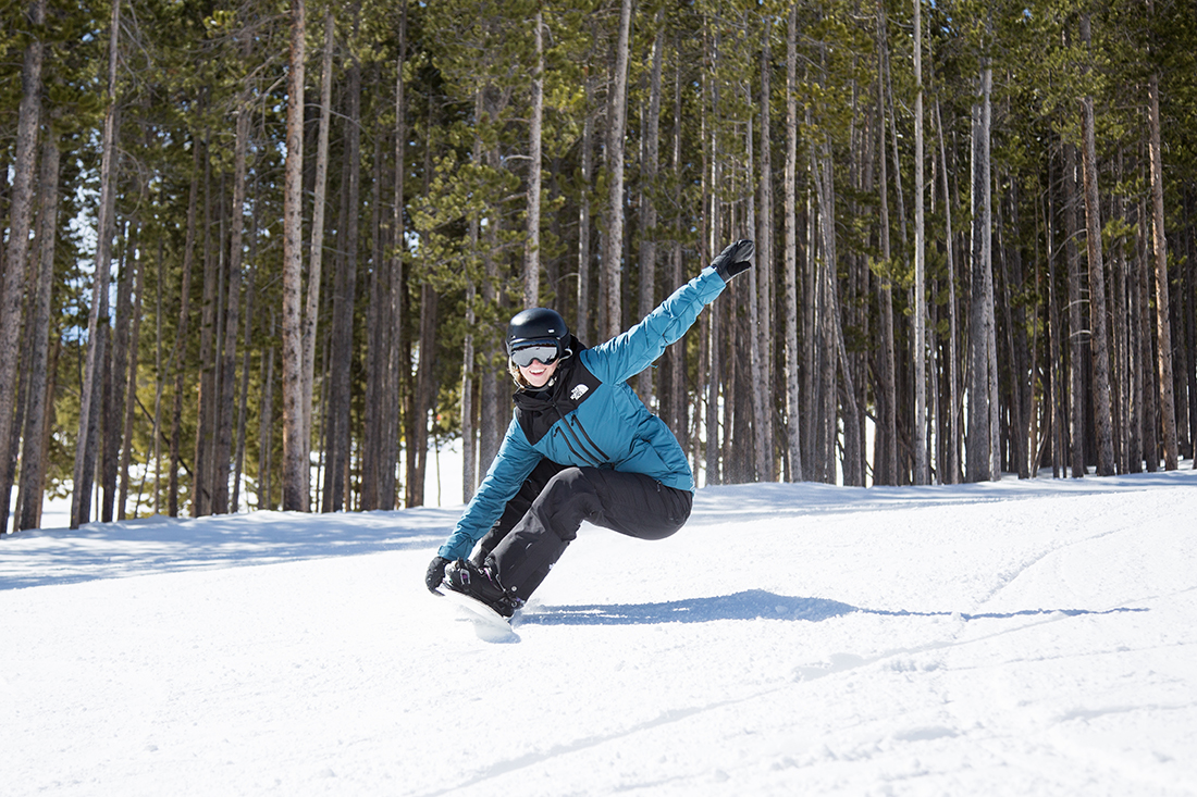 Lyndsey Stevens snowboards with her arm extended up